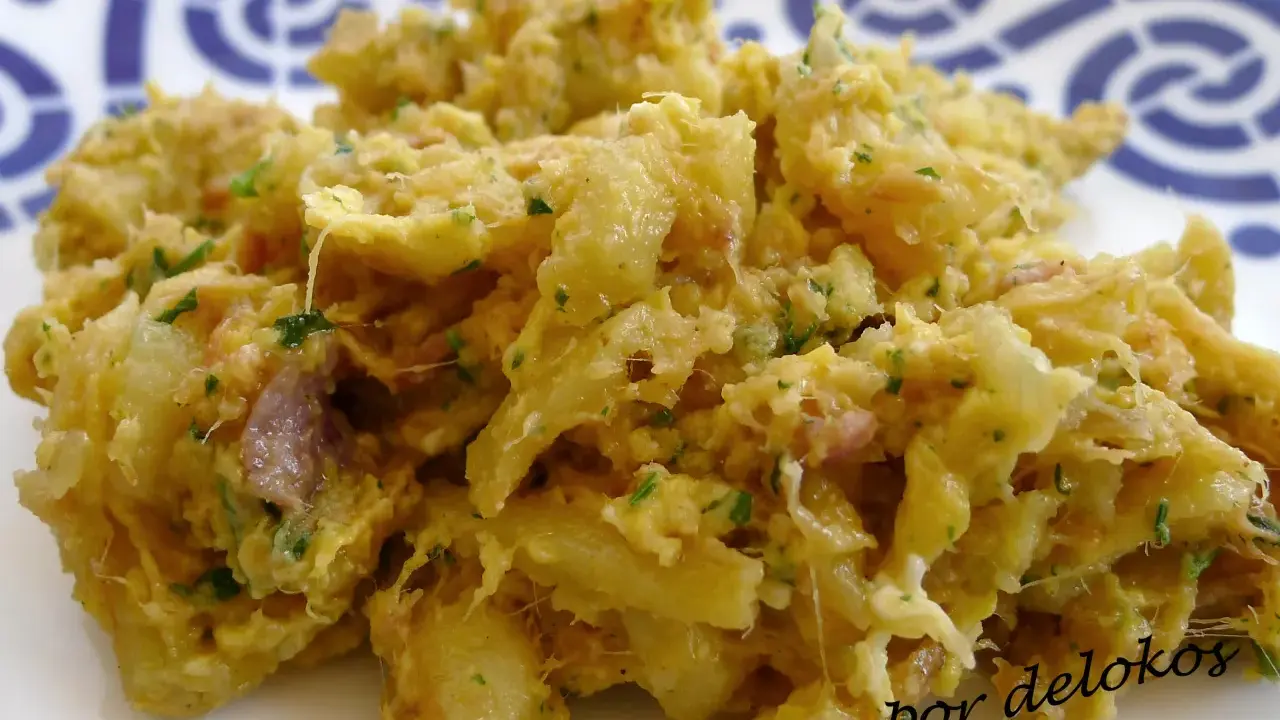 Un plato de alheira que es una deliciosa mezcla desmenuzada de carne, patatas y hierbas, servido en un plato blanco con un patrón azul.
