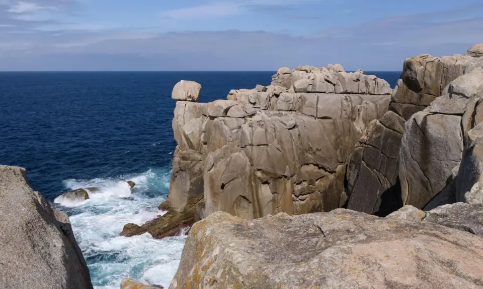 Impresionantes acantilados de papel se alzan sobre el mar azul, con olas rompiendo en su base.
