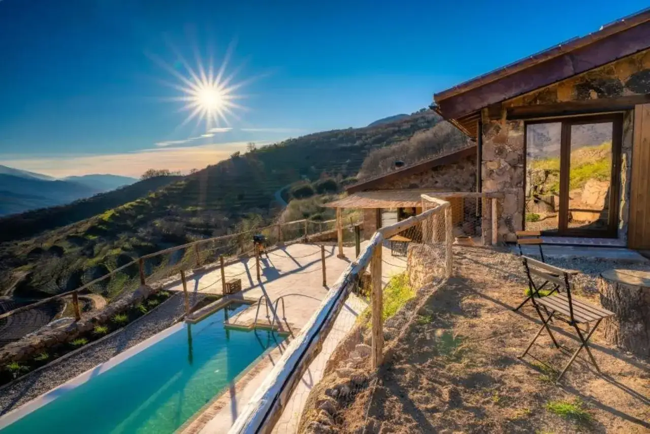 Casa rural balcón del camino viejo. Piscina y terraza con vistas a las montañas bajo un sol radiante.