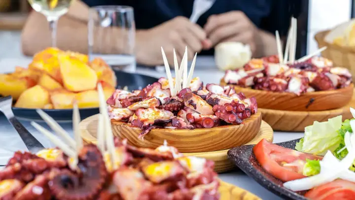 Deliciosa comida gallega: pulpo a la gallega servido en cuencos de madera, acompañado de patatas y ensalada.